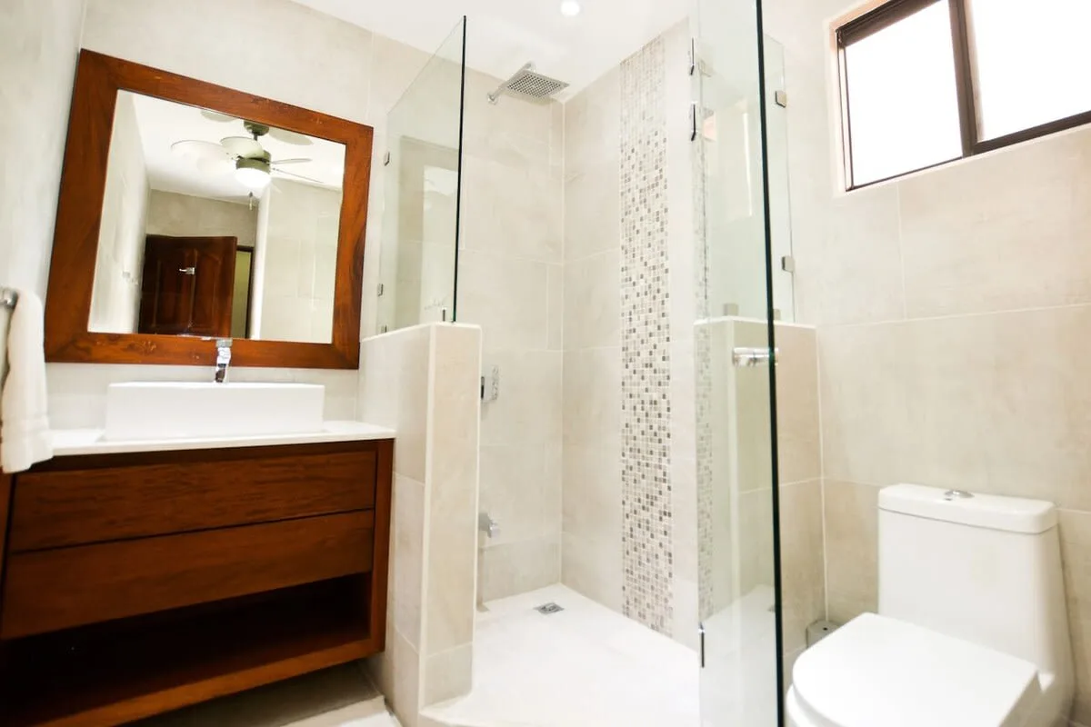 A bright bathroom with a vanity, mirror, and glass shower.