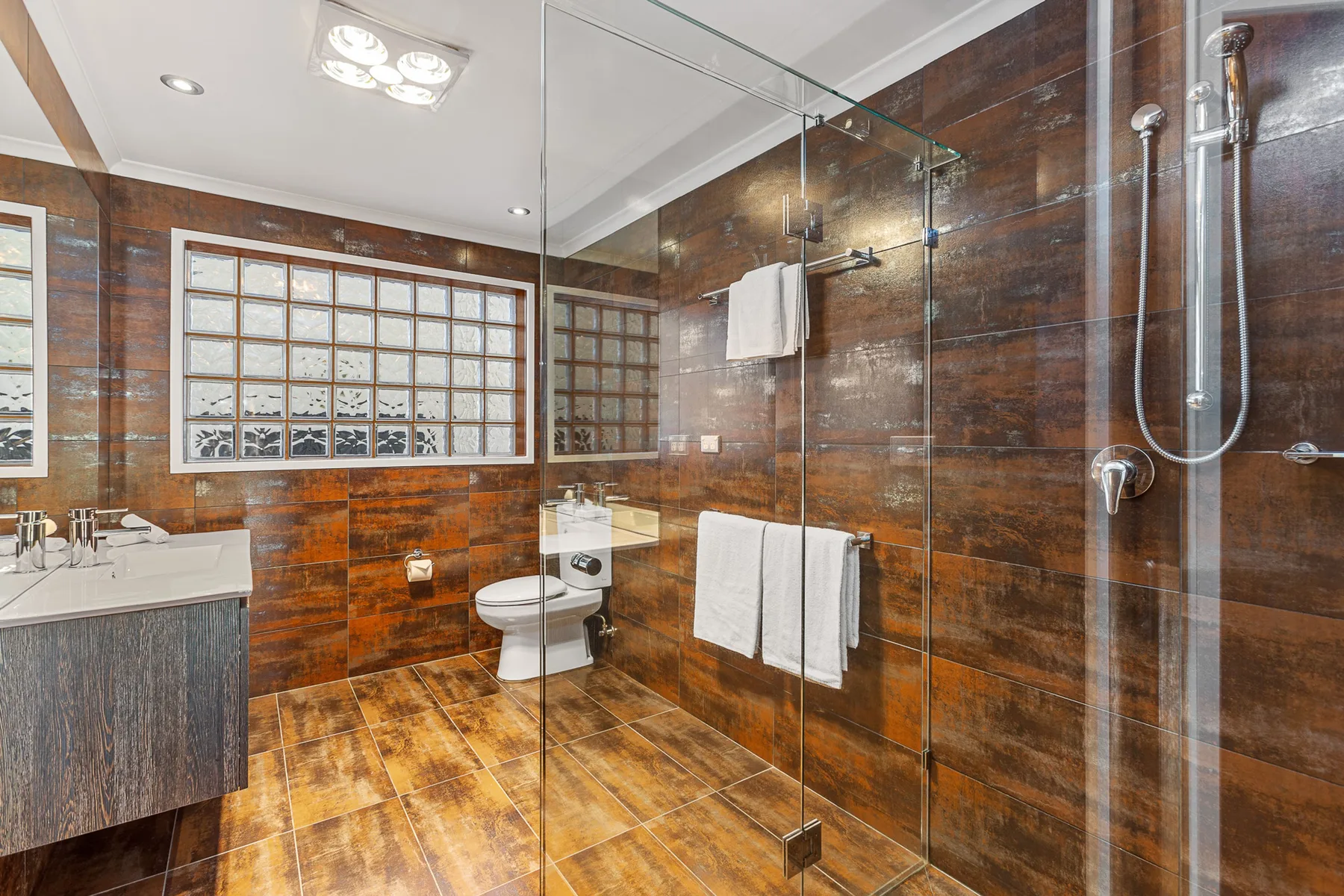 A bathroom with a glass shower and a vanity.