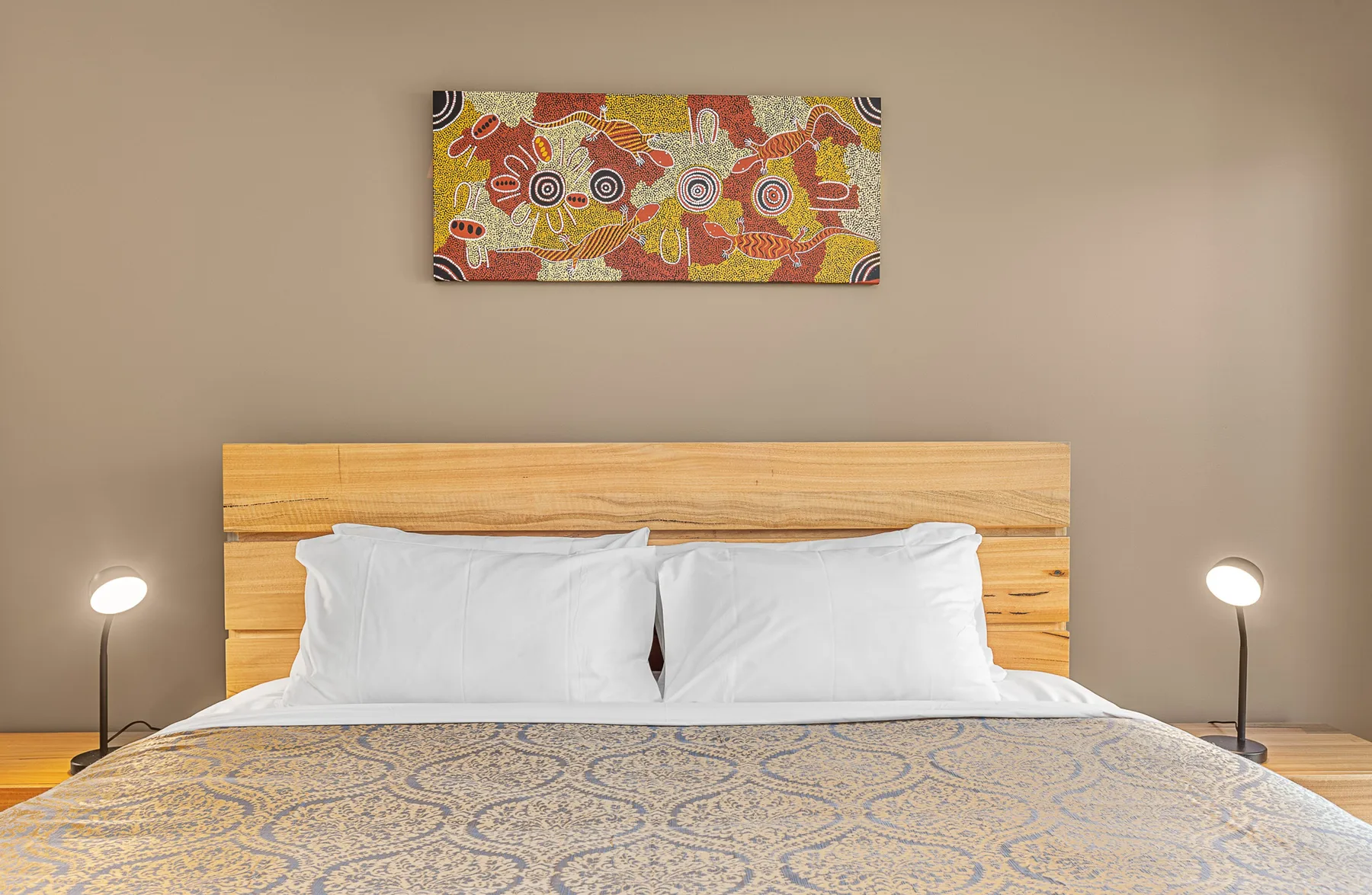 A bedroom with a neatly made bed beneath colorful wall art.