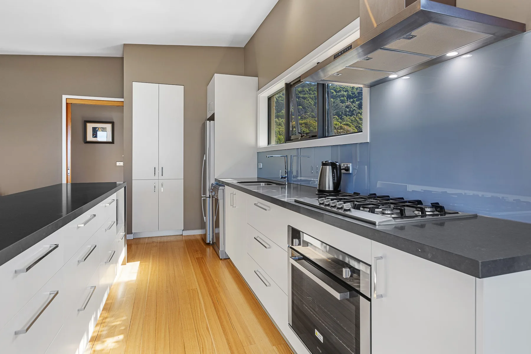 A modern kitchen with white cabinets, dark countertops, and a stainless steel range.