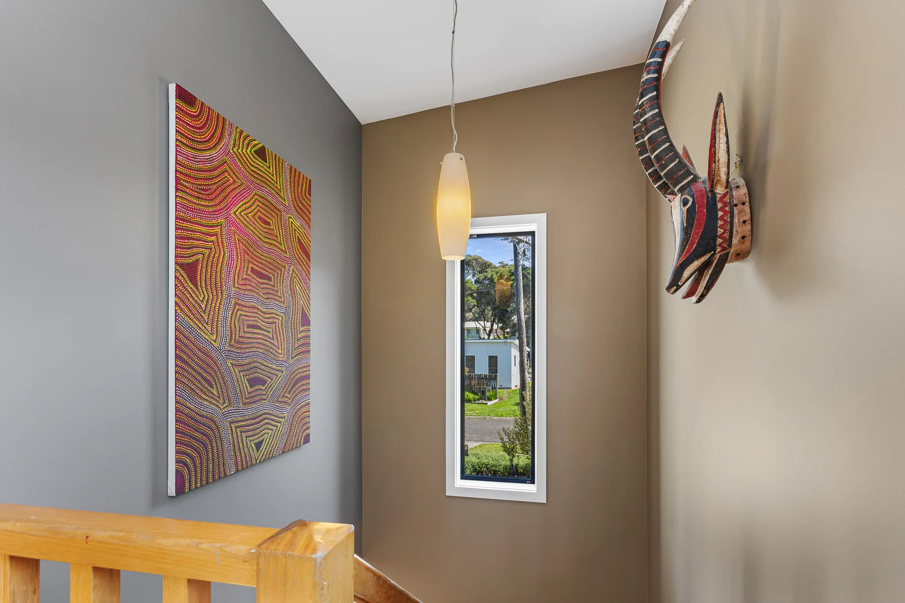 A stairwell with colorful wall art and a narrow window.