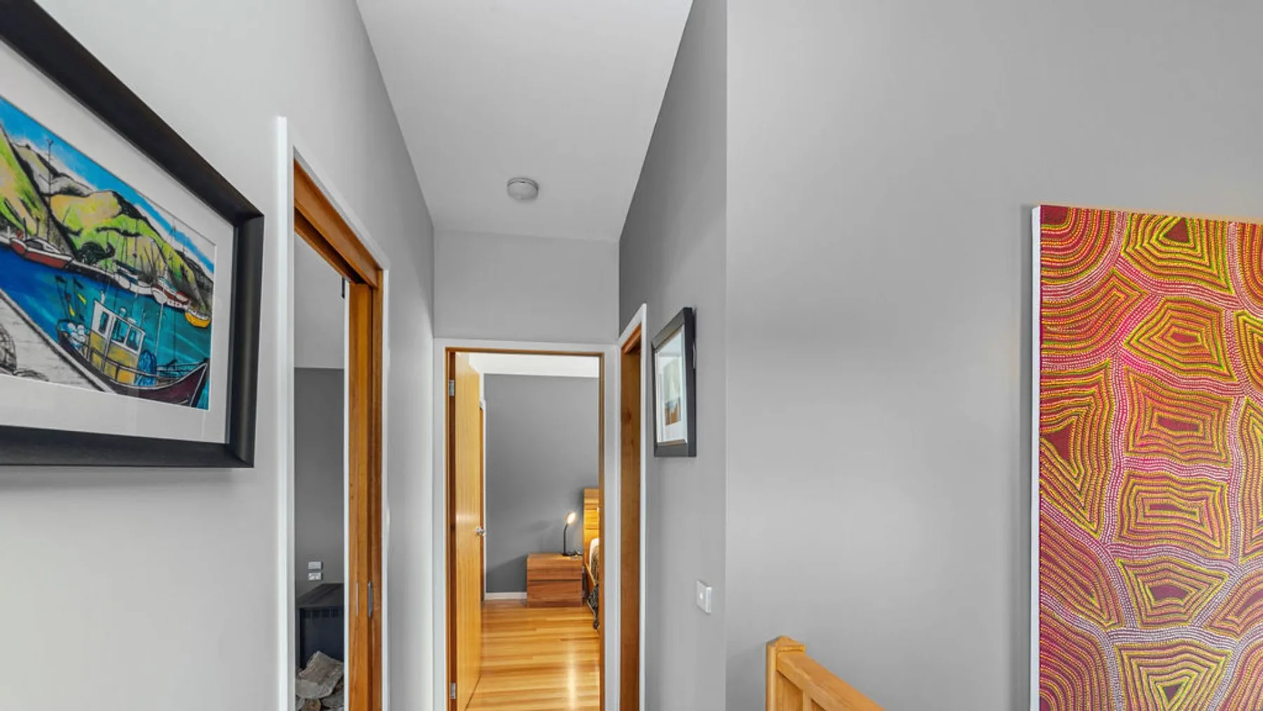 A hallway with wooden doorways and colorful framed artwork on the walls.