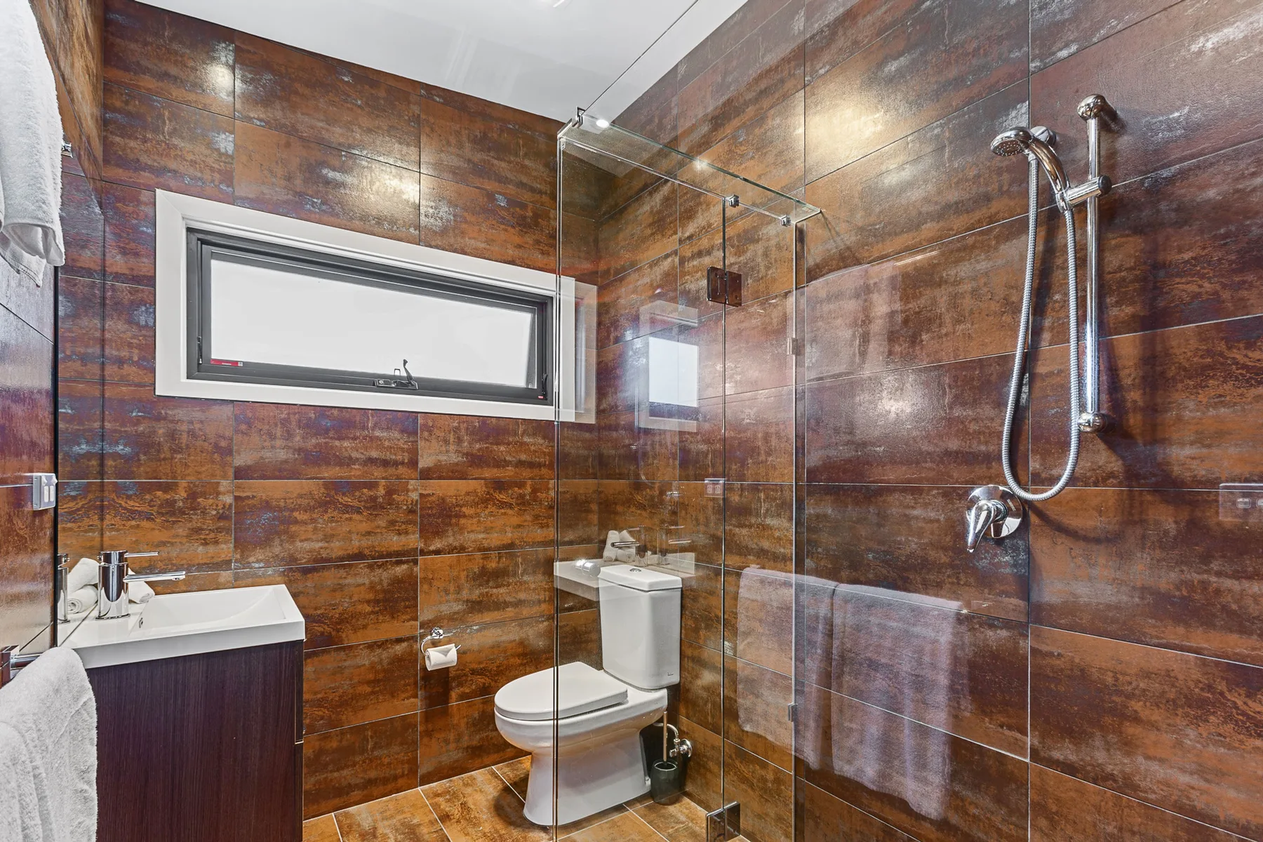 A tiled bathroom with a glass shower and a vanity.