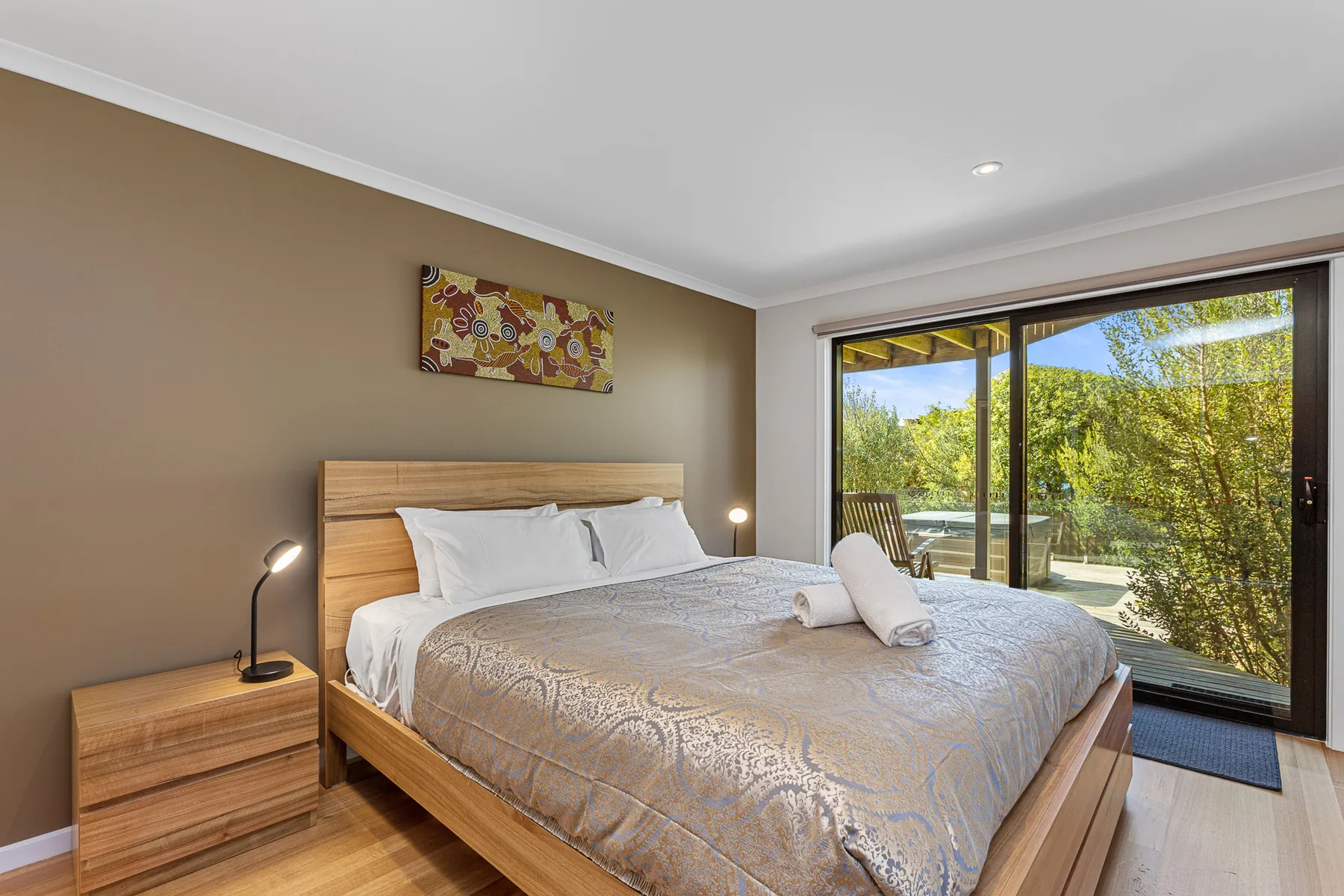 A bedroom with a made bed beside a large sliding glass door.