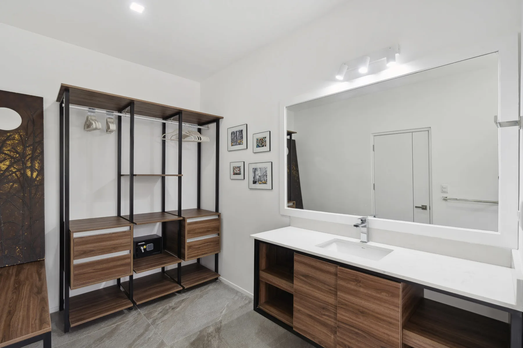 A bright dressing area with open shelving and a long vanity beneath a large mirror.