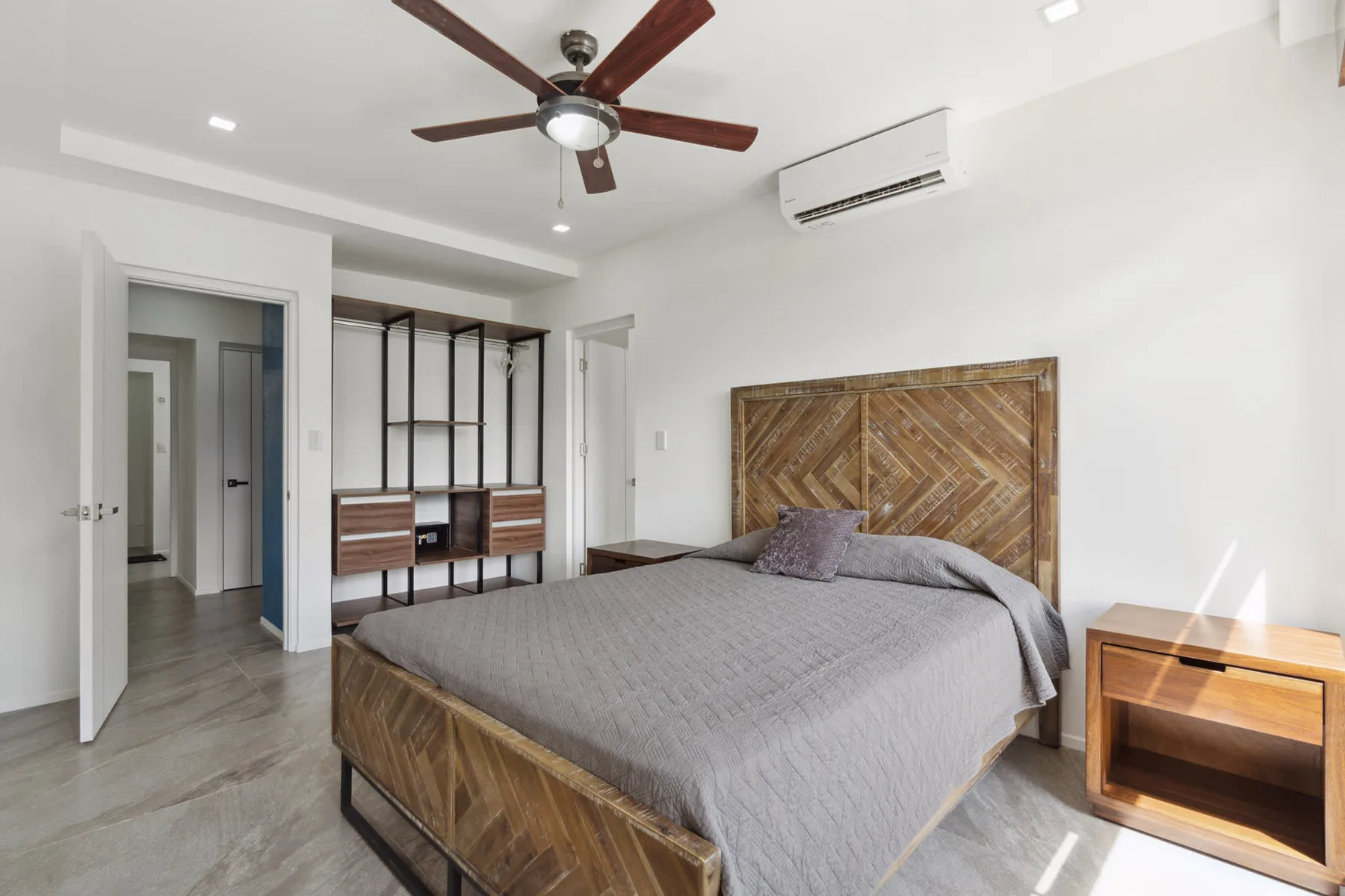 A bedroom with a bed, patterned wooden headboard, and open shelving.