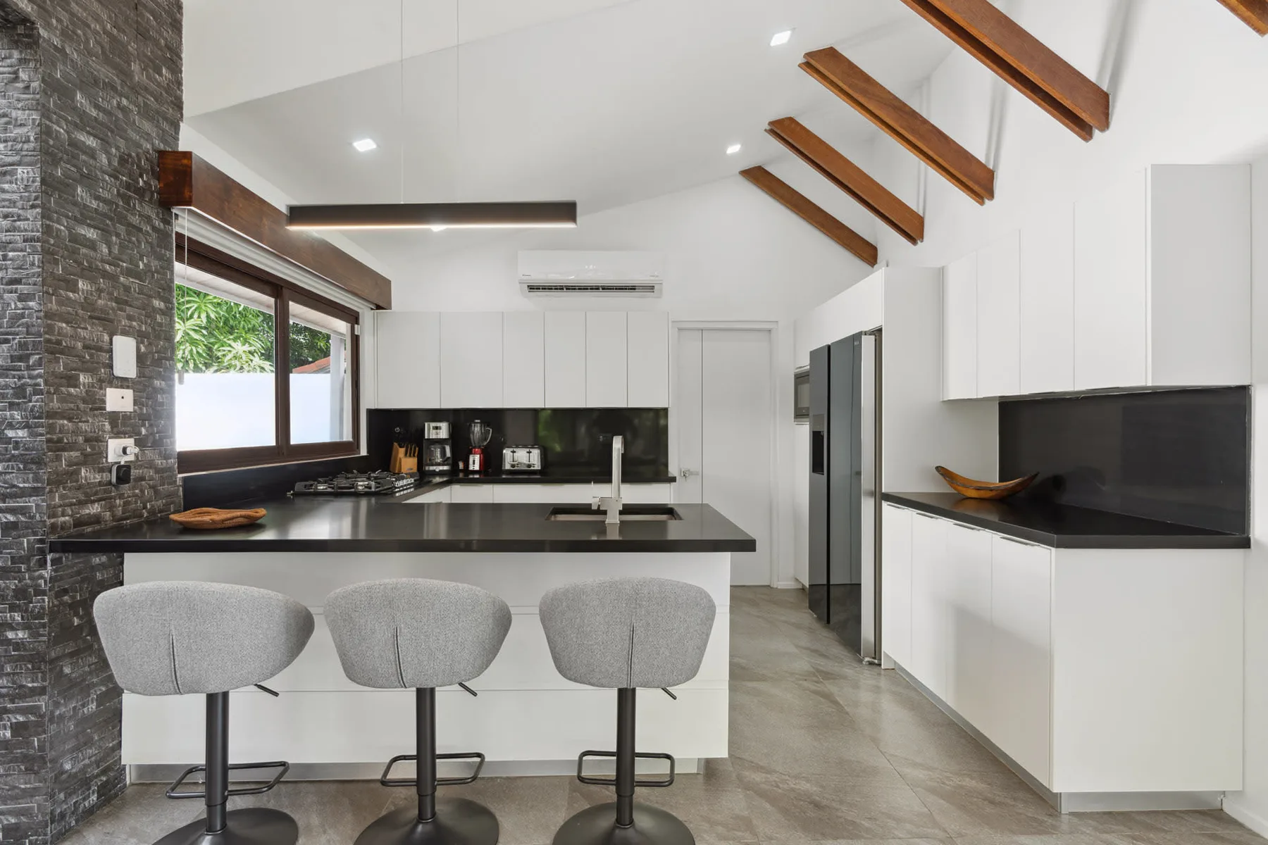 A modern kitchen with a central island, bar seating, and white cabinetry.