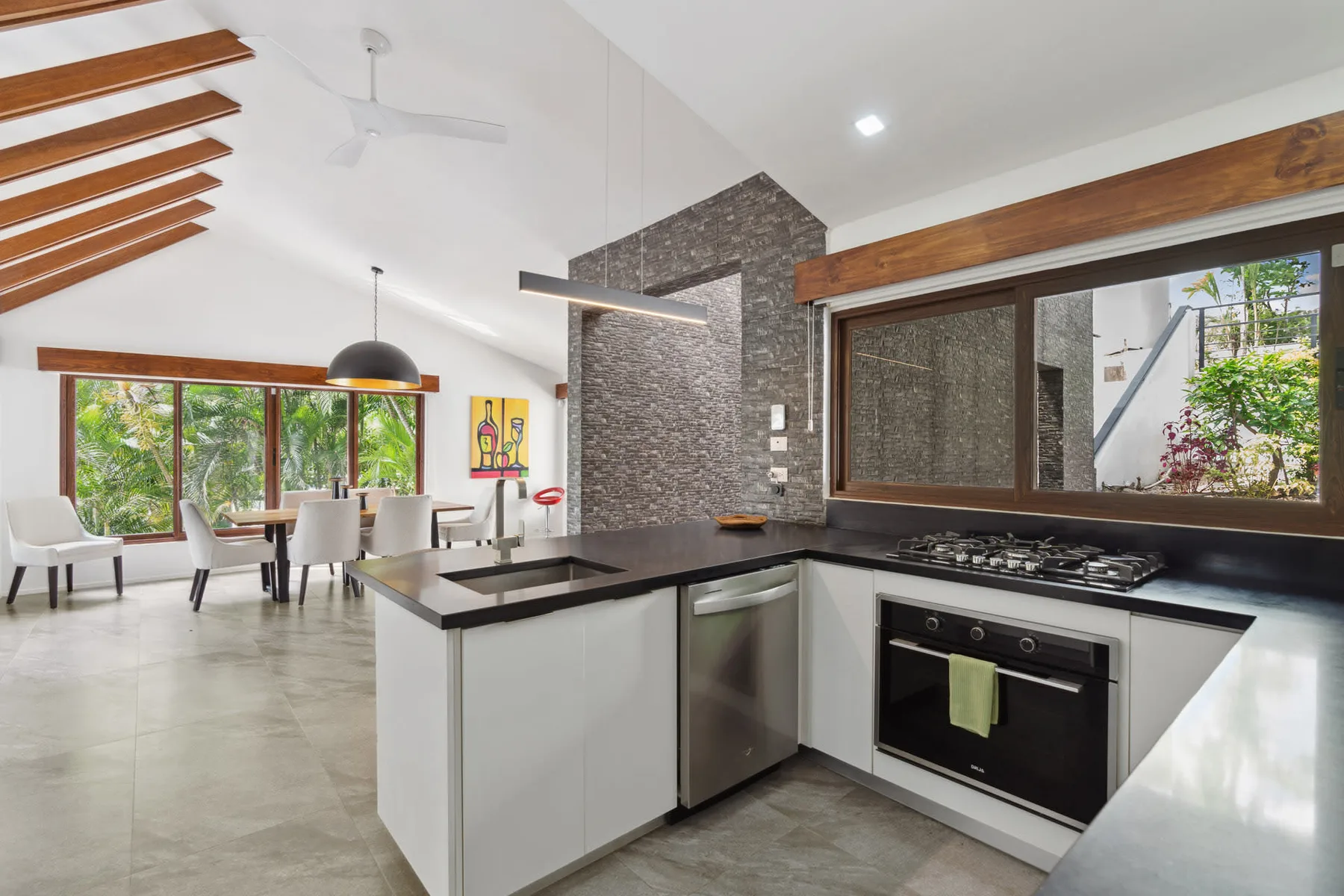 A modern kitchen opens onto a dining area with large windows.