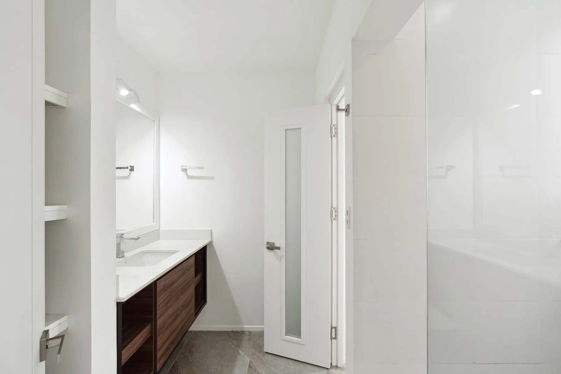 A bright bathroom with a vanity, mirror, and glass shower.