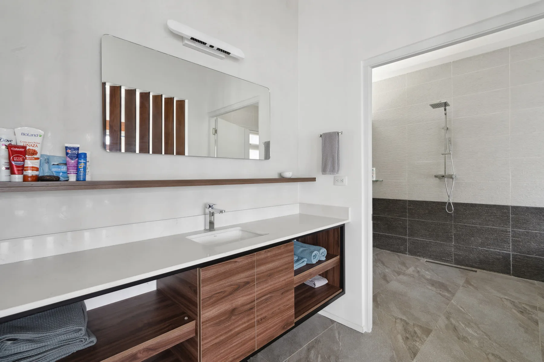 A modern bathroom with a long vanity and an open shower area.