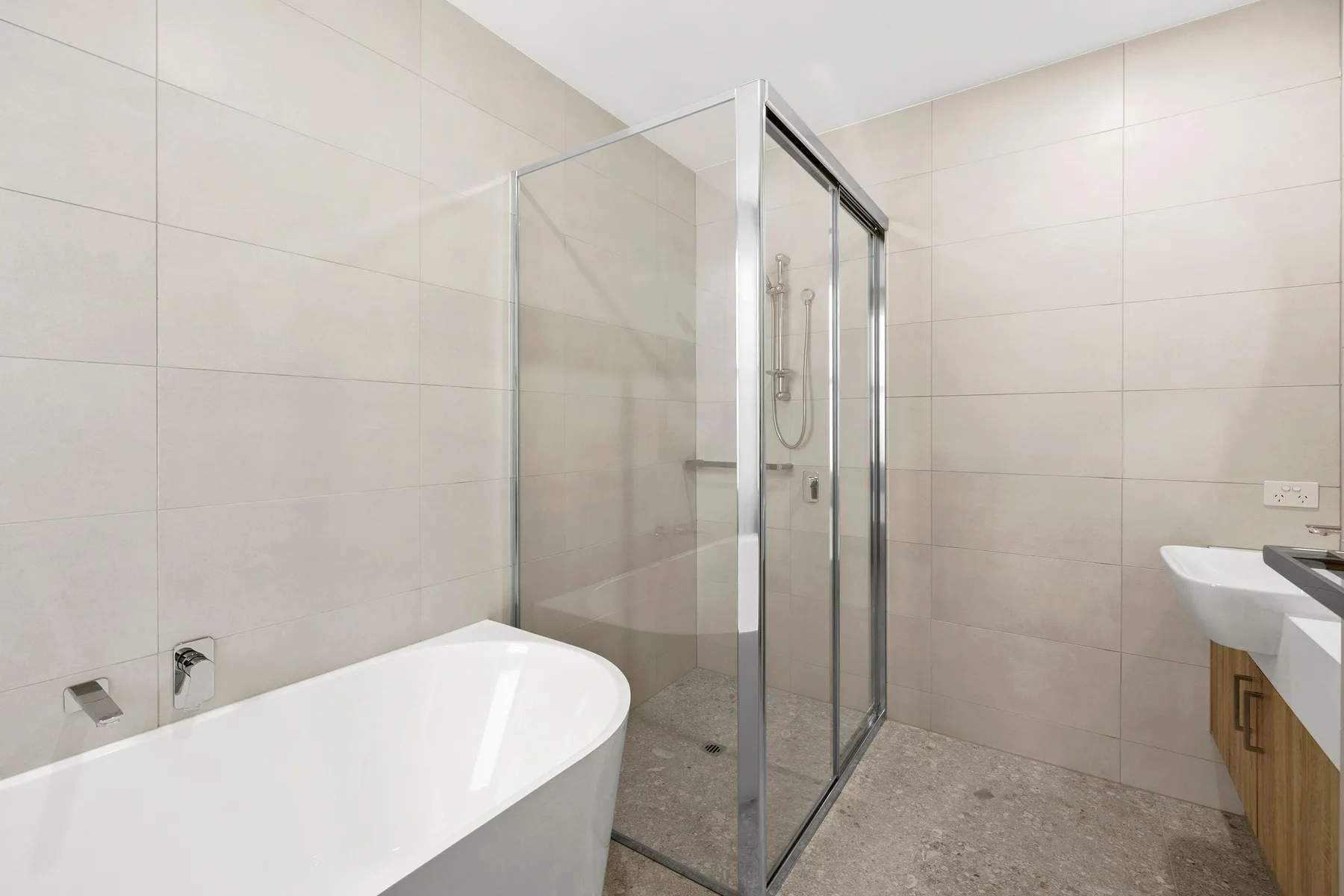 Baño alicatado con bañera, ducha de vidrio y lavabo.