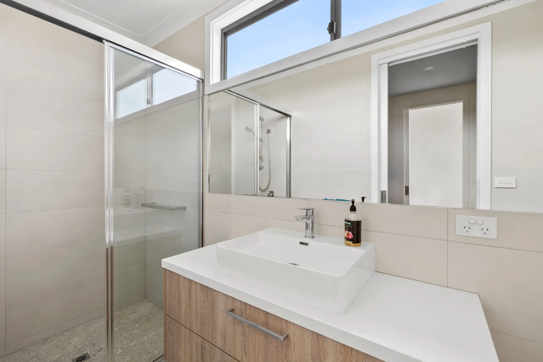 Un baño luminoso con ducha de cristal y un amplio lavabo.