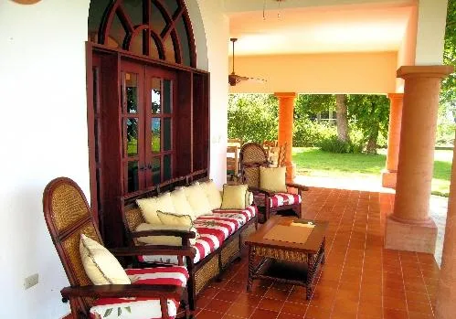 A covered veranda with seating, a coffee table, and a garden view.