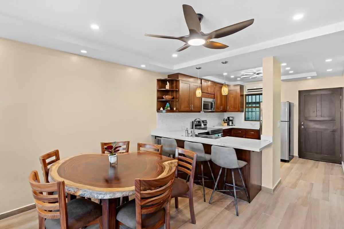 Dining area with a round table and an open kitchen behind it.