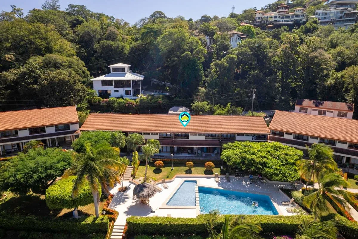 Shared amenity: Aerial view of a swimming pool surrounded by landscaped grounds and buildings.