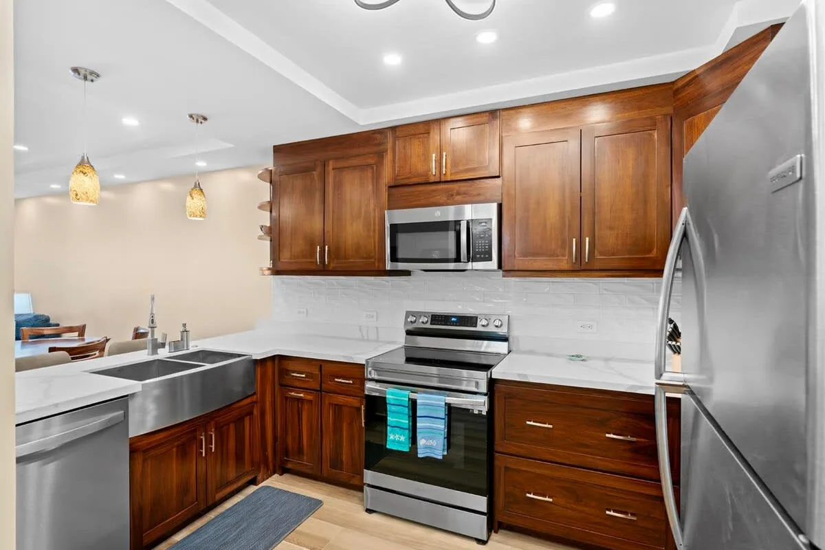 A kitchen with wooden cabinets, stainless steel appliances, and light countertops.