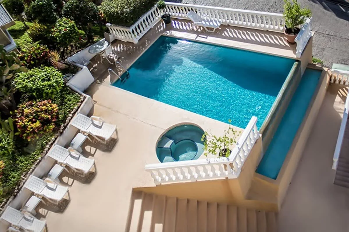 Shared amenity: An outdoor swimming pool and hot tub sit beside a sunlit patio.