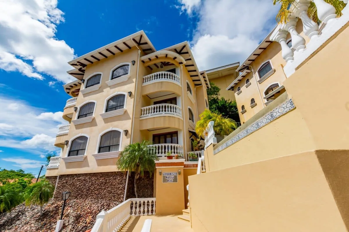 Shared amenity: Multi-story building with balconies and a stairway beneath a blue sky.