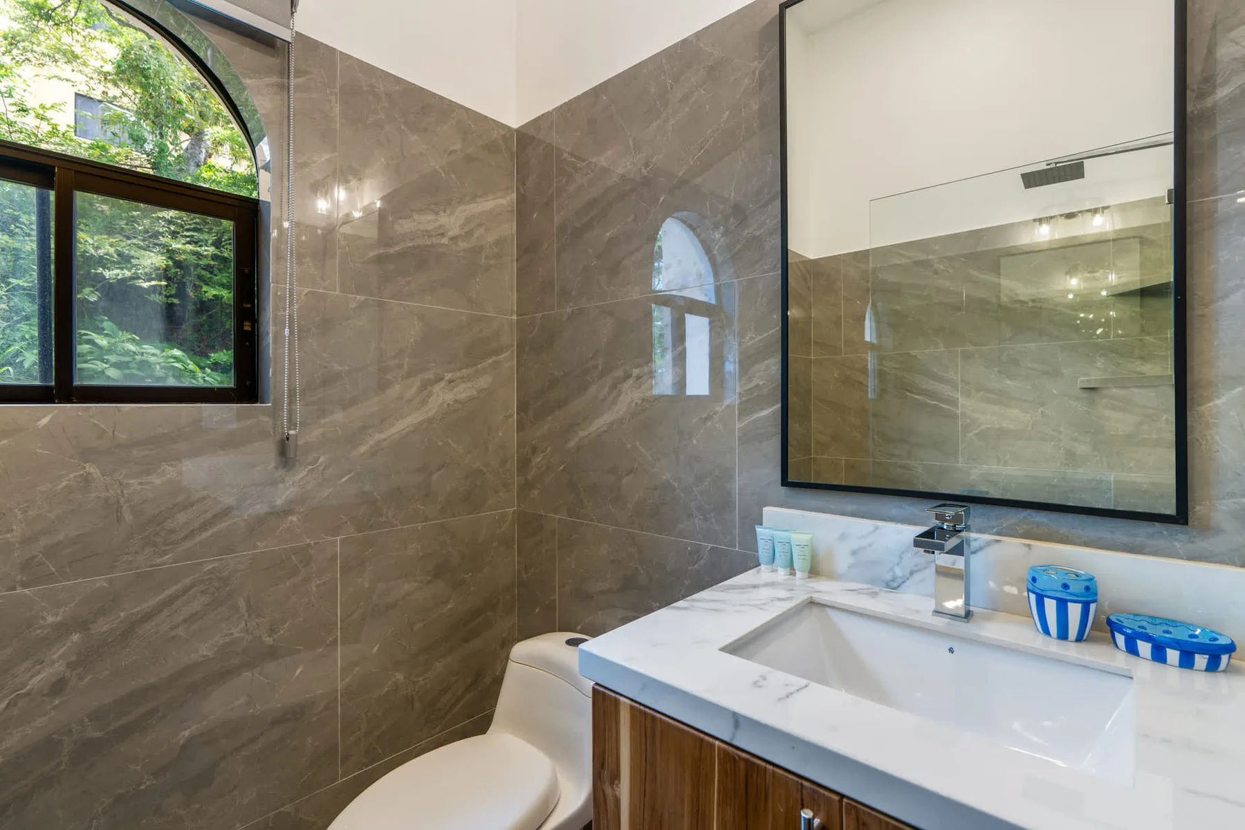A bathroom with a sink, toilet, and arched window.