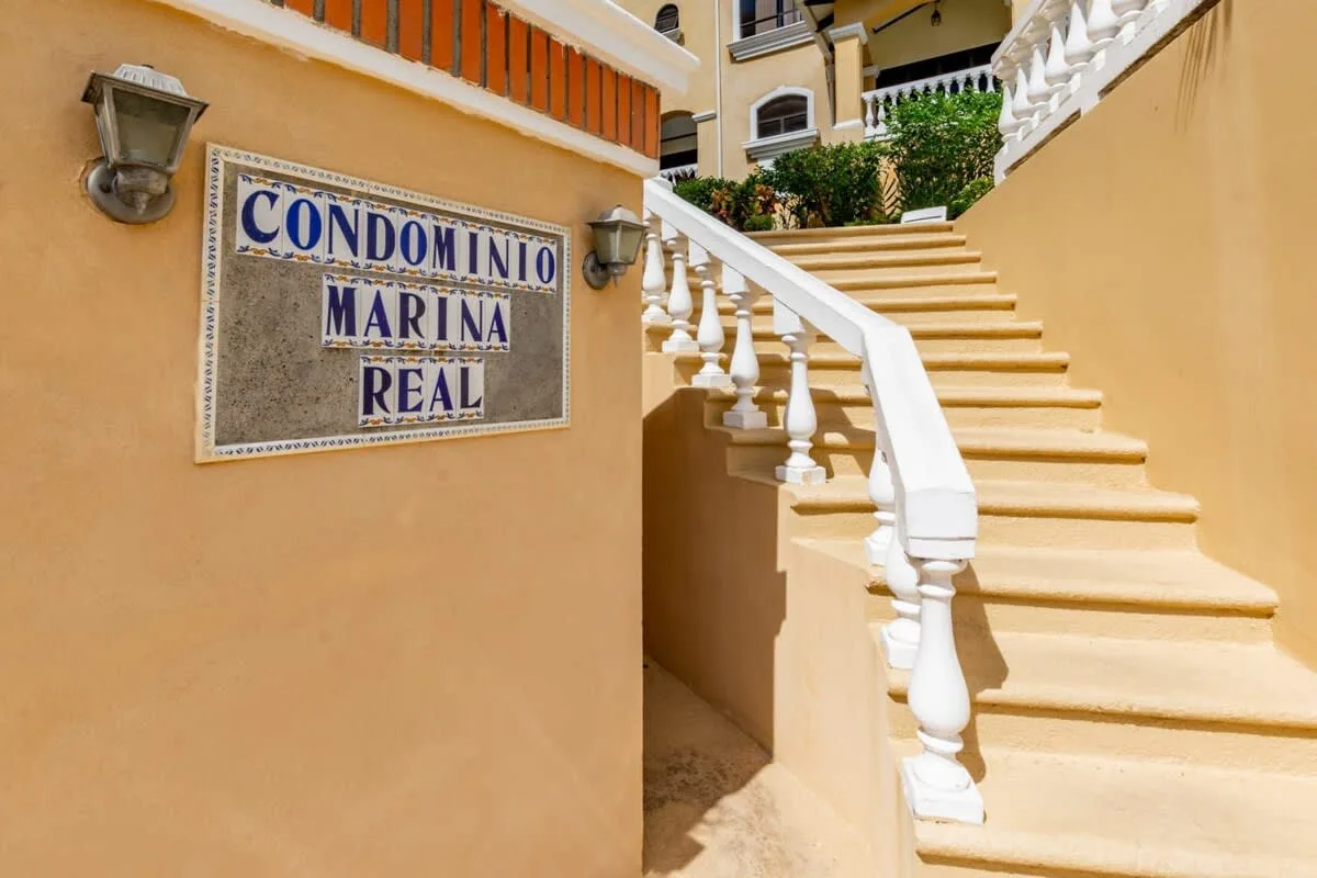 Shared amenity: An exterior staircase with white railings leads up beside a wall-mounted sign.
