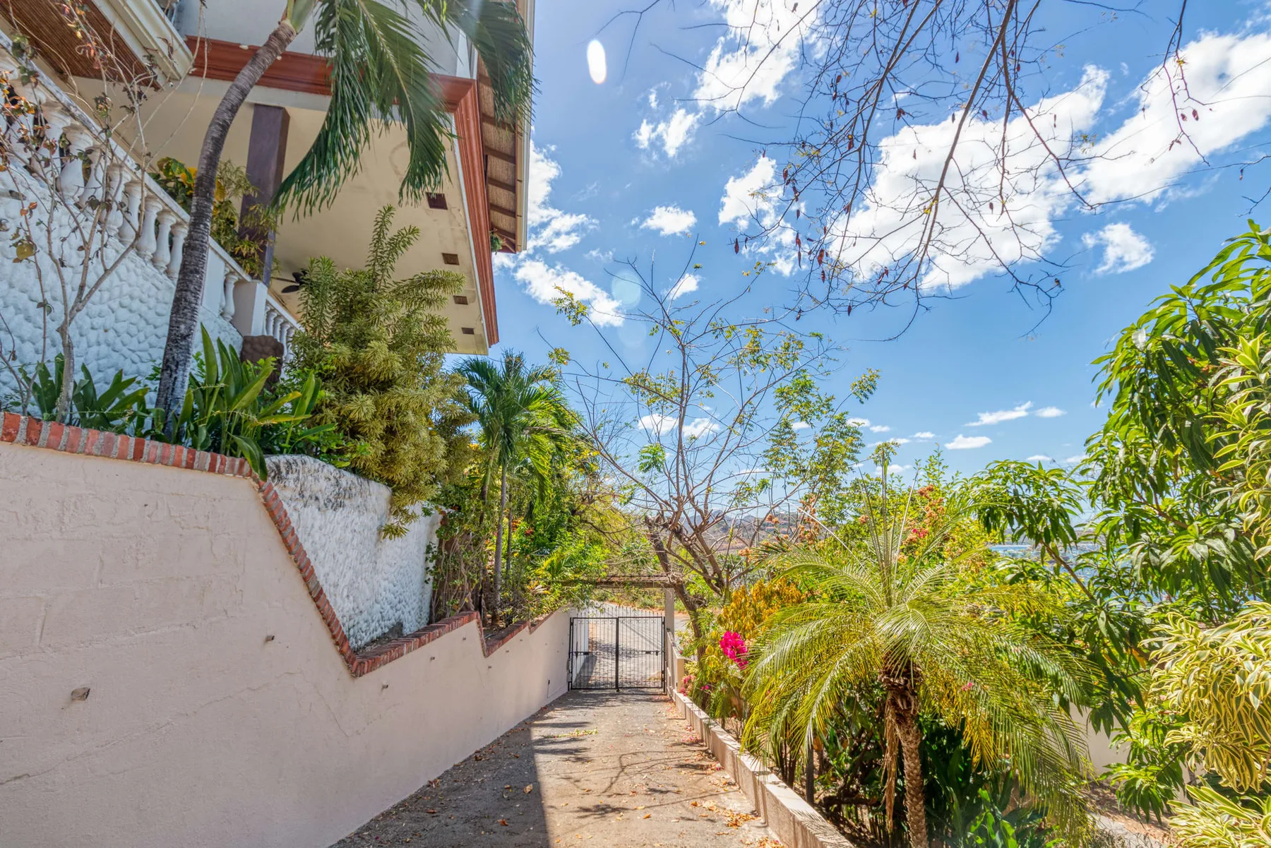 A paved outdoor path runs beside a building and lush greenery.