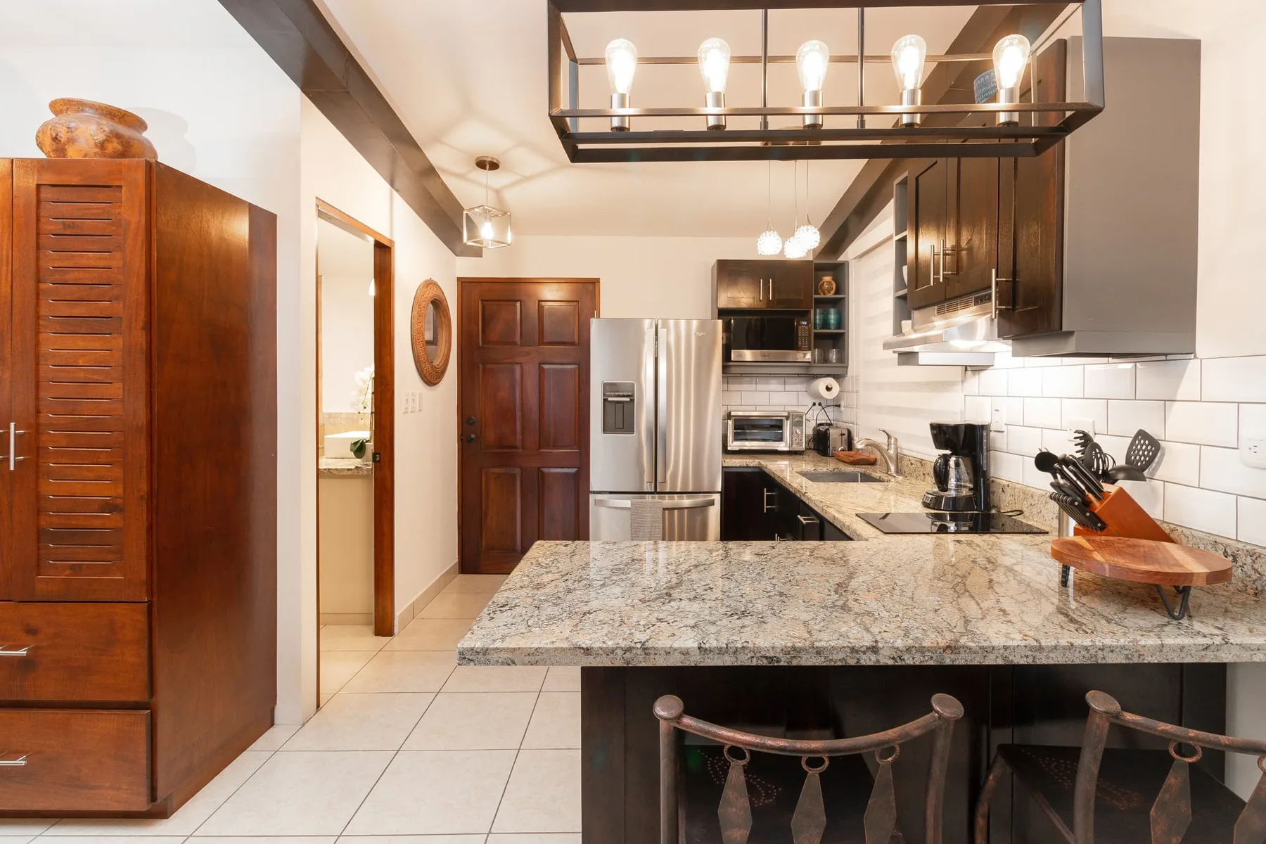 A kitchen with dark cabinets, stainless steel appliances, and a large stone island.