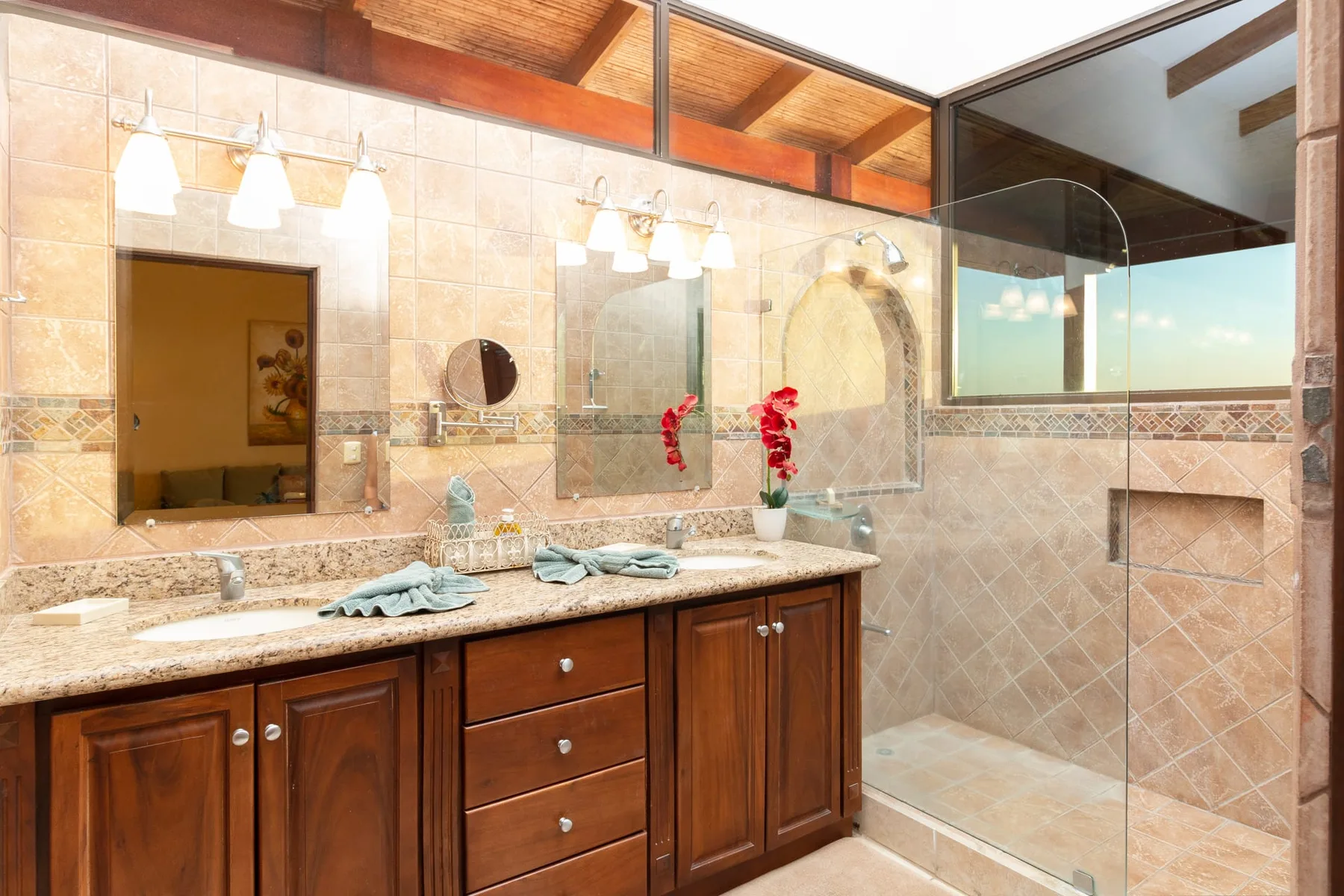A bathroom with a double vanity, mirrors, and a glass shower.