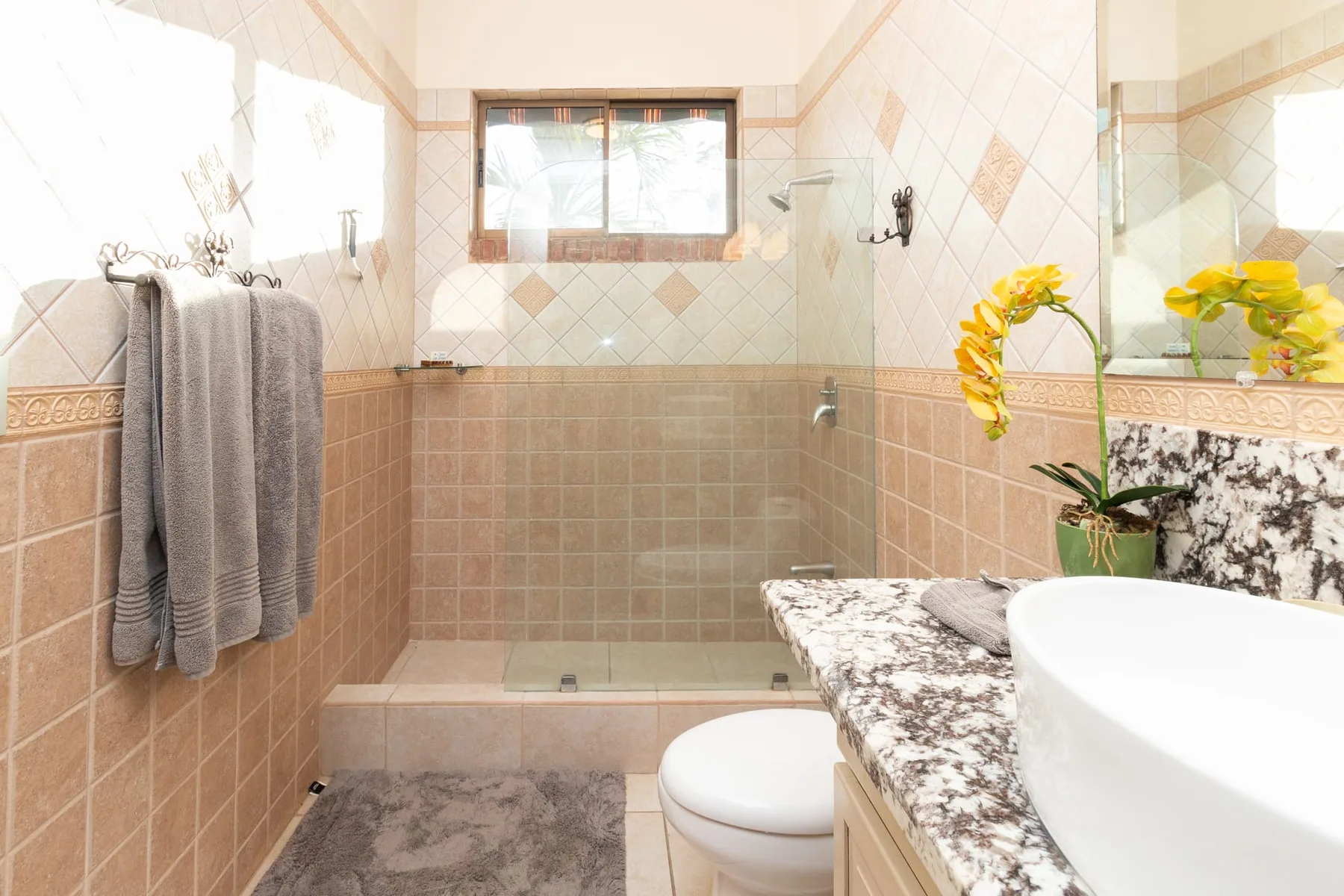 A tiled bathroom with a bathtub, a separate shower area, and a flower arrangement.