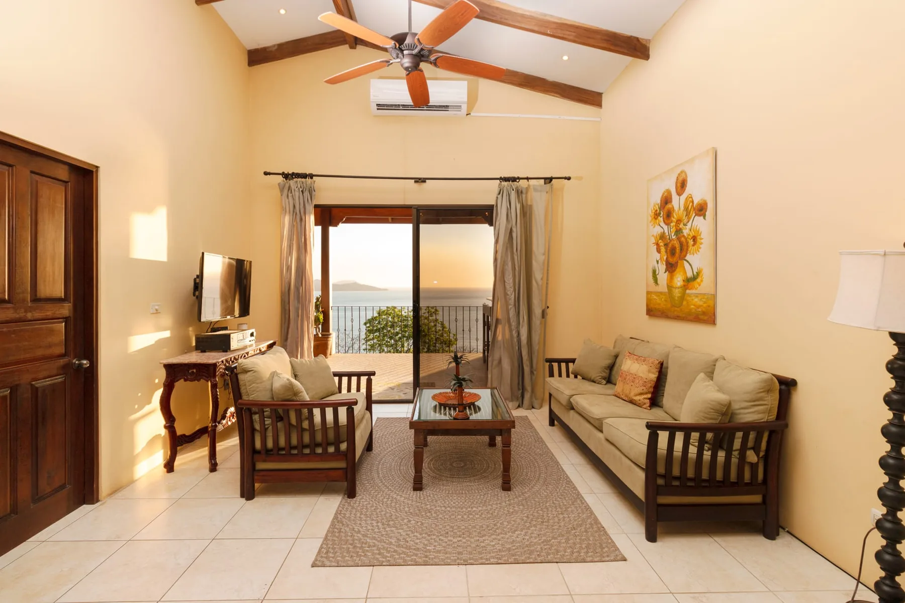 A living room with seating around a coffee table and sliding glass doors opening to a balcony.
