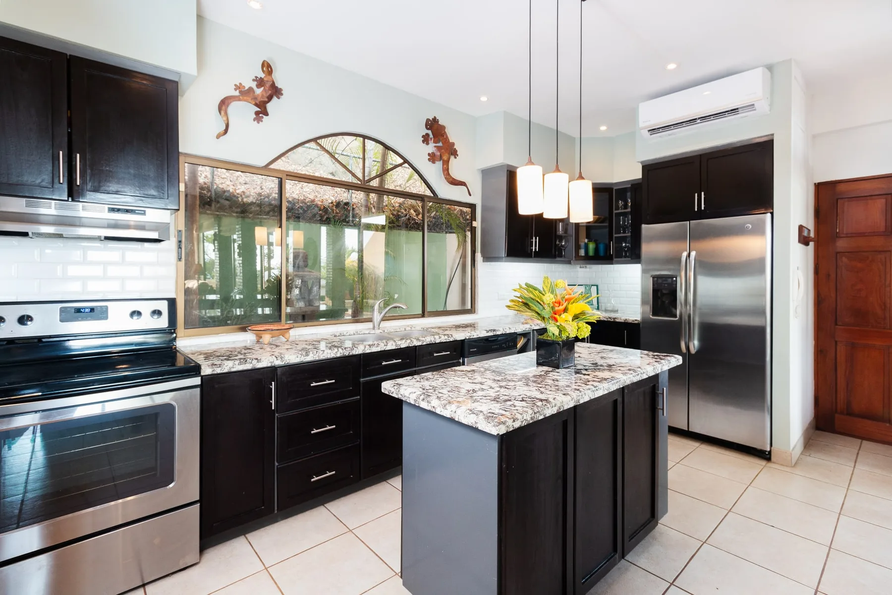 A bright kitchen with dark cabinets, stainless steel appliances, and a central island.