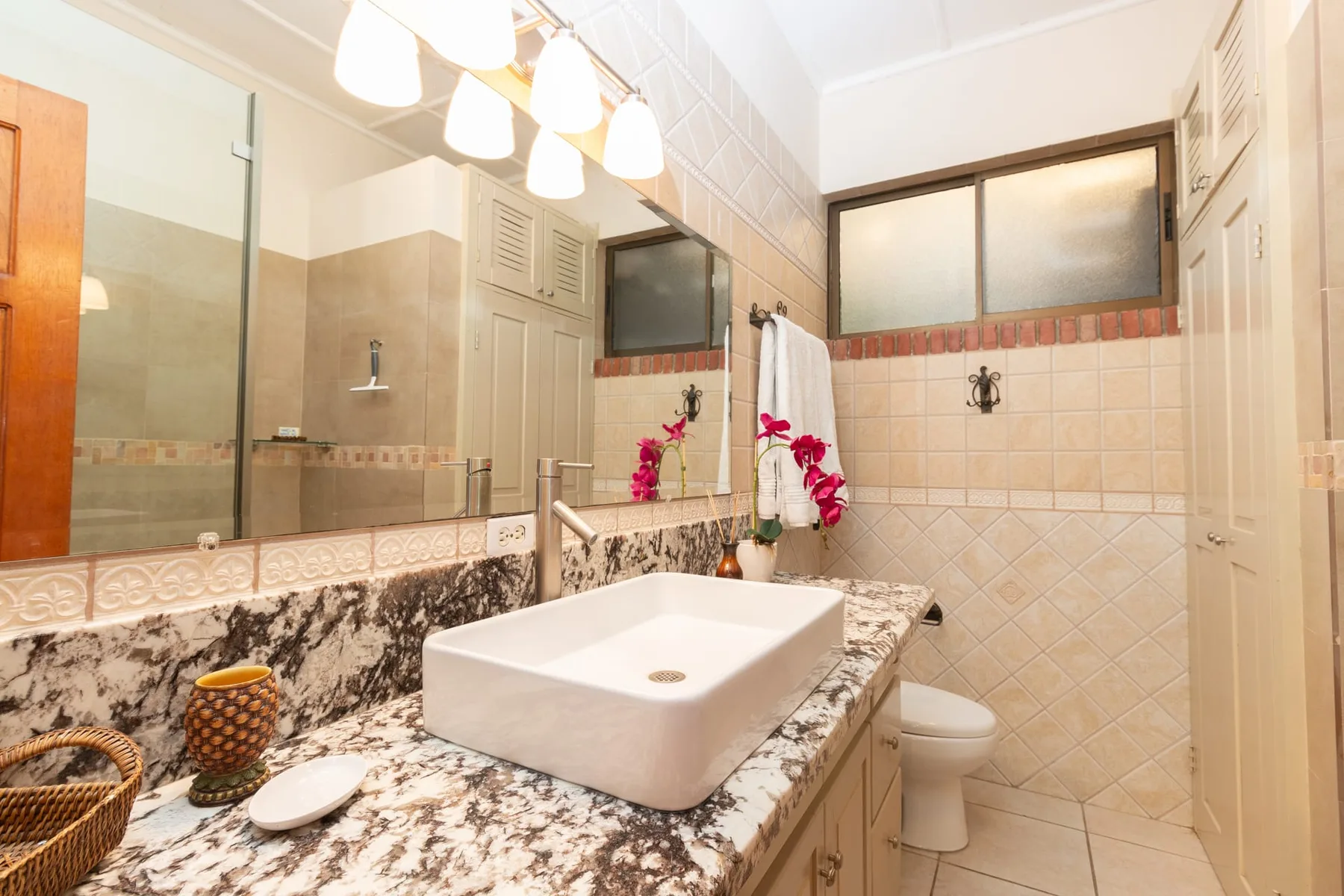A bathroom with a wide vanity, vessel sink, and tiled shower area.