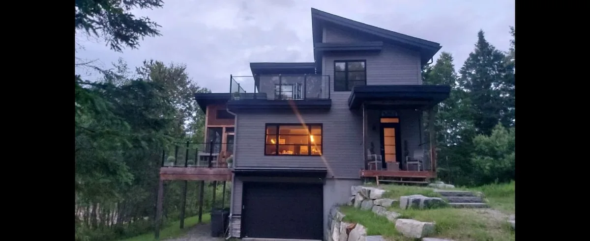 Una casa moderna con garaje integrado, rodeada de árboles.