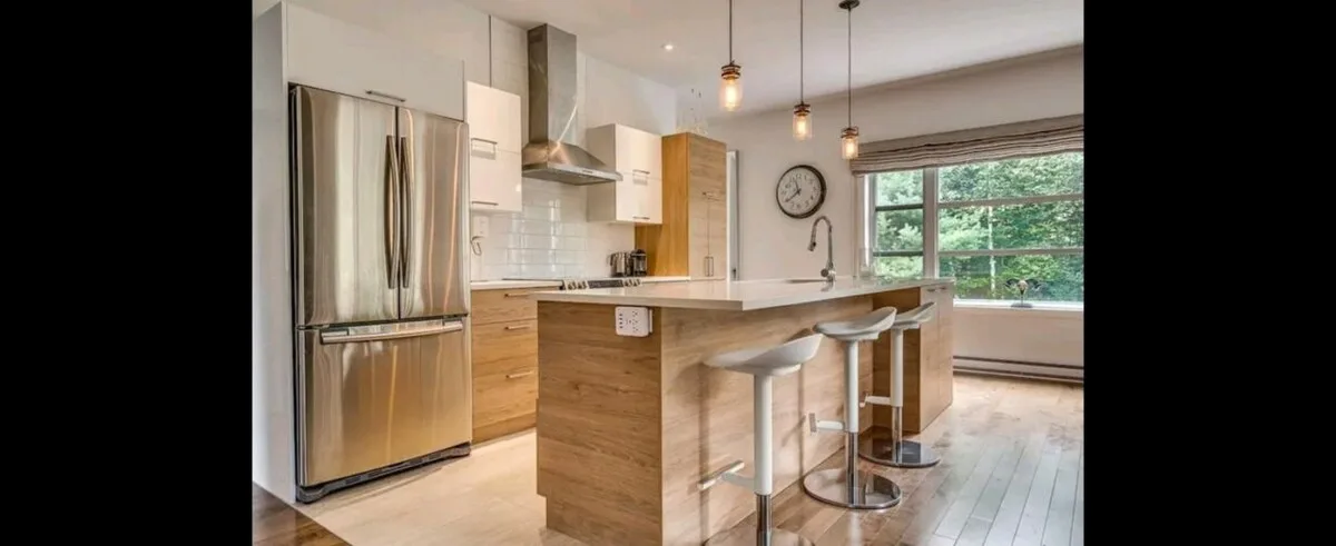 Una cocina luminosa con una isla central, electrodomésticos de acero inoxidable y una ventana grande.