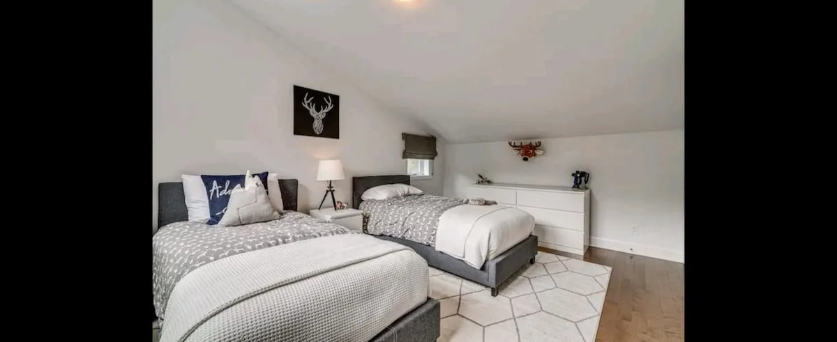 Un dormitorio con dos camas, una cómoda y una alfombra clara.