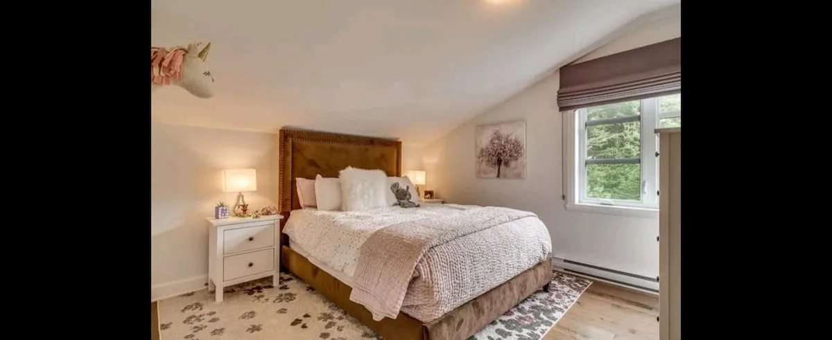 Dormitorio con una cama grande, una mesita de noche y una ventana.