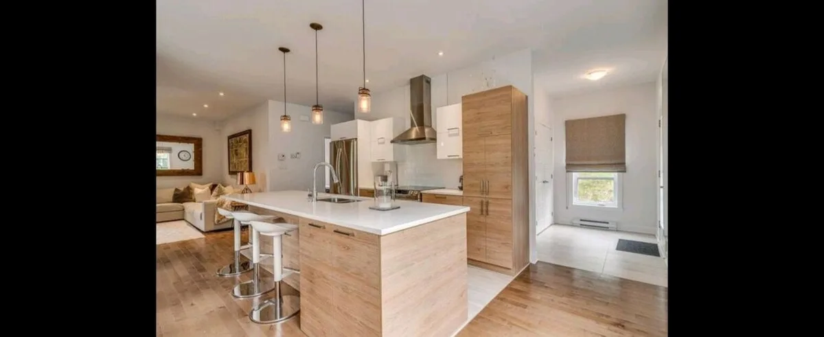 Una cocina luminosa con una isla de acabado de madera y luces colgantes.