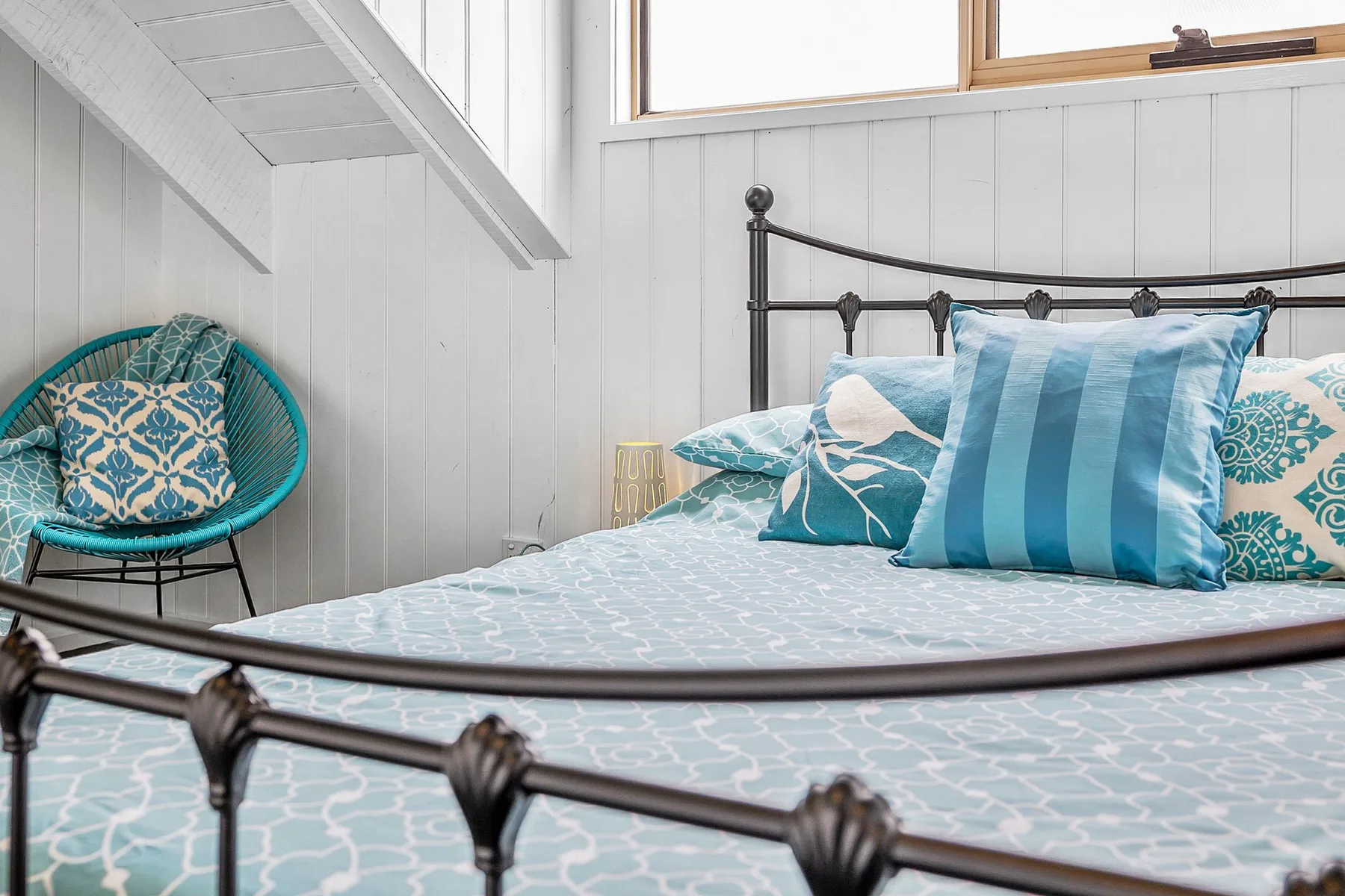 Un dormitorio con una cama de metal y ropa de cama azul estampada.