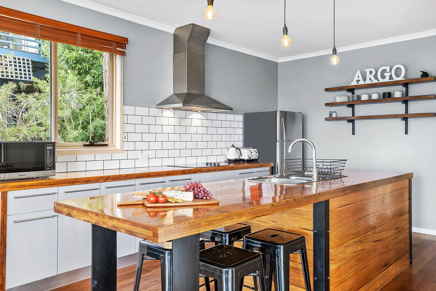 Una cocina moderna con isla de madera, salpicadero de azulejos y ventana.