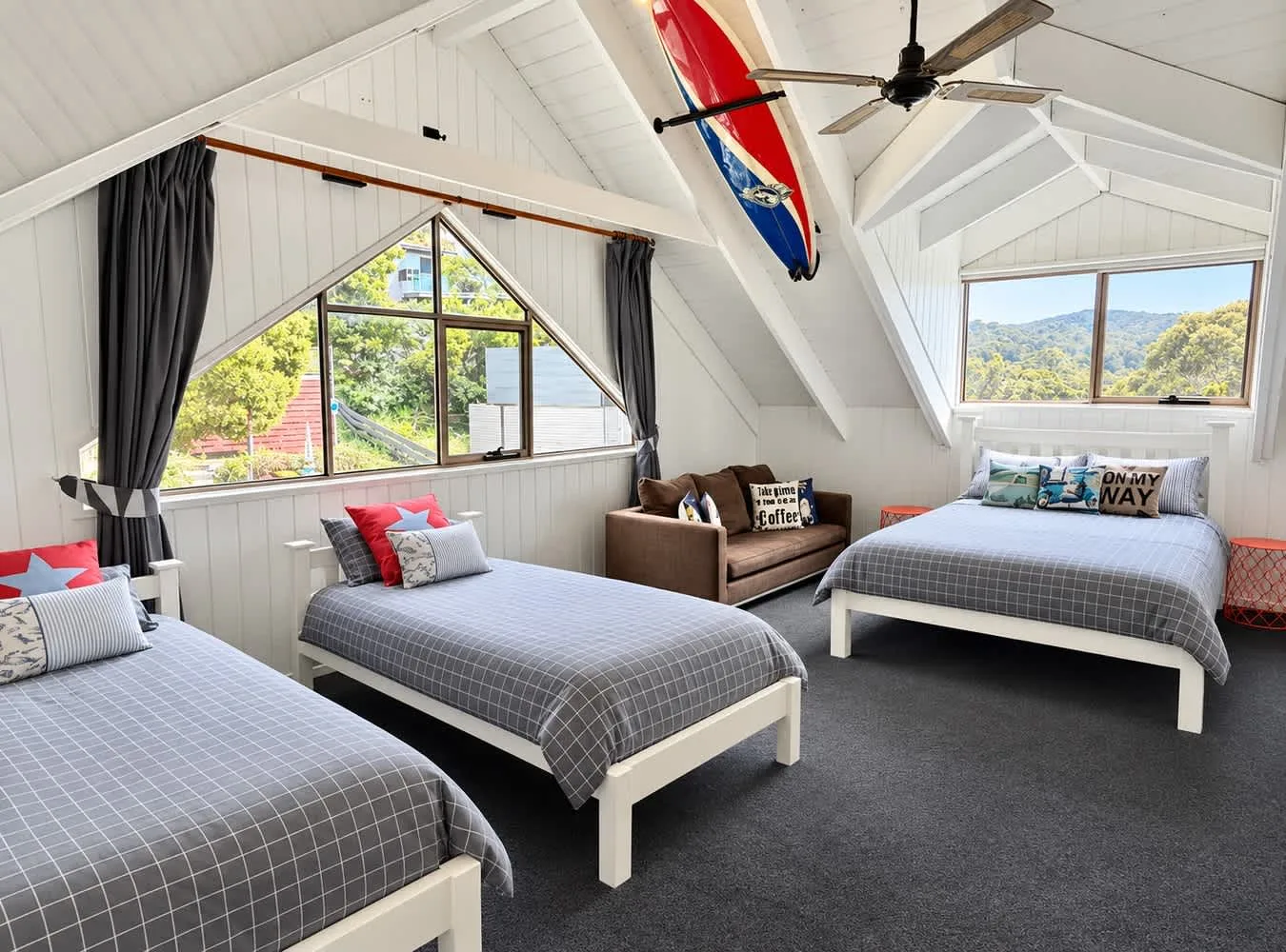 Un dormitorio abuhardillado luminoso con camas bajo techos blancos inclinados.