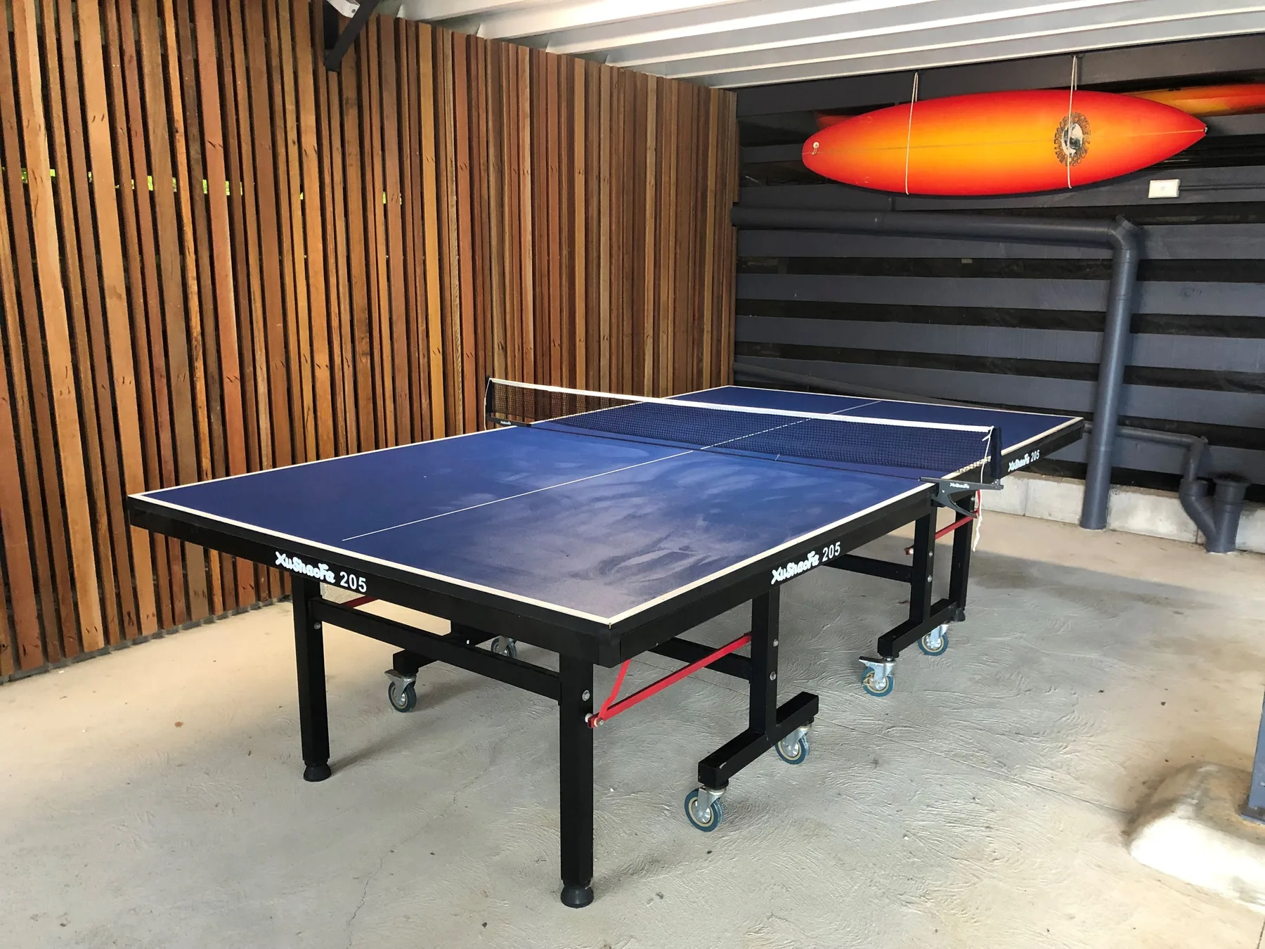 Una mesa de tenis de mesa está en un área recreativa cubierta con paredes de listones de madera.