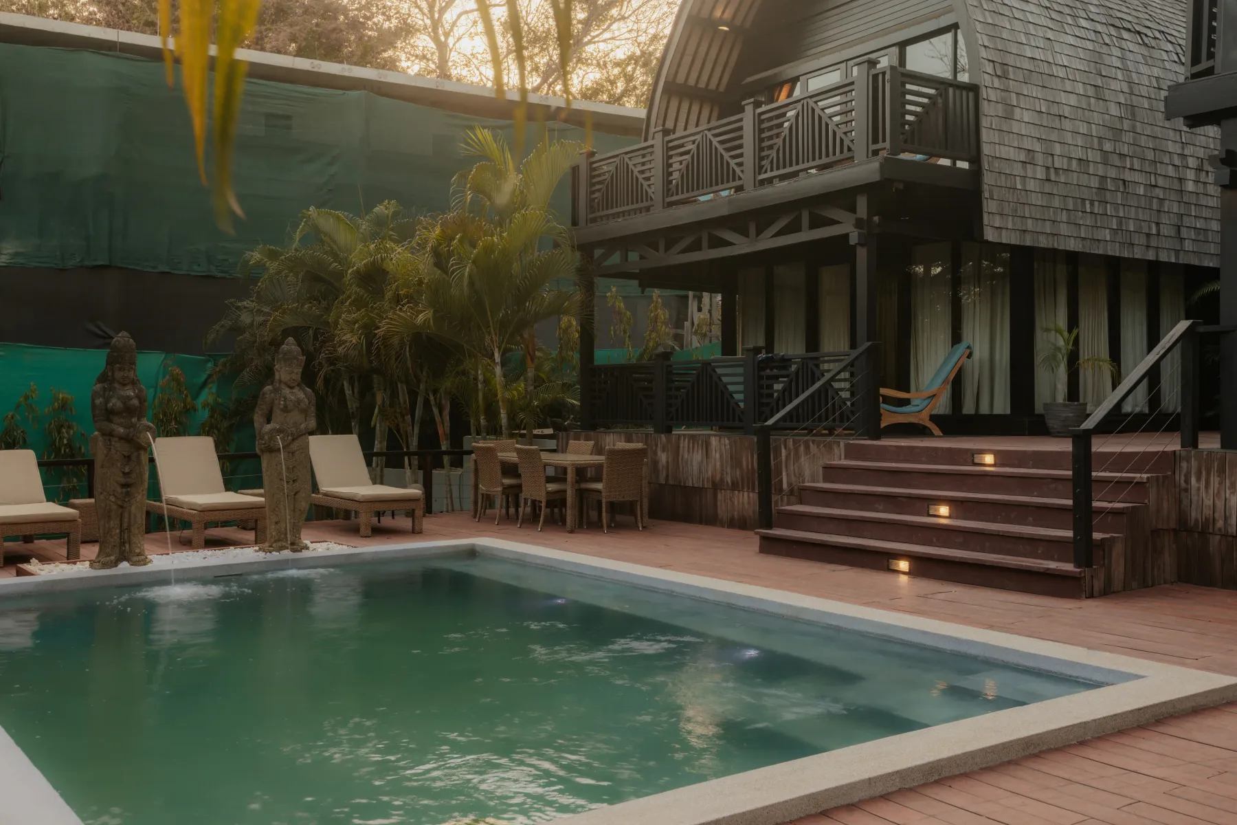 Zona común: Una piscina en un patio está junto a una terraza de madera con asientos al aire libre y un edificio de varios niveles.