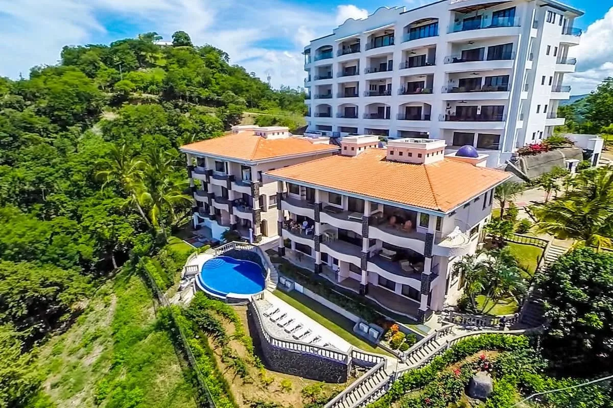 Shared amenity: An aerial view of multi-story buildings beside a small outdoor pool and green hillside.