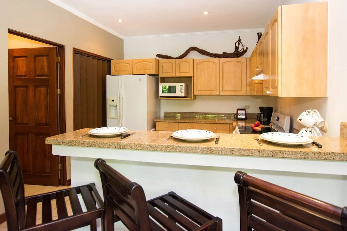 A kitchen with a breakfast bar and wooden cabinets.