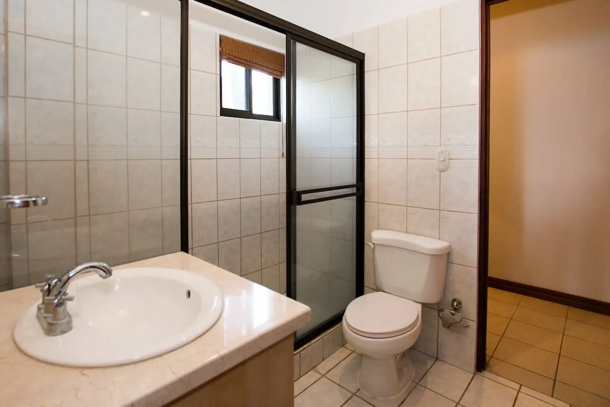 A tiled bathroom with a sink, toilet, and glass shower enclosure.