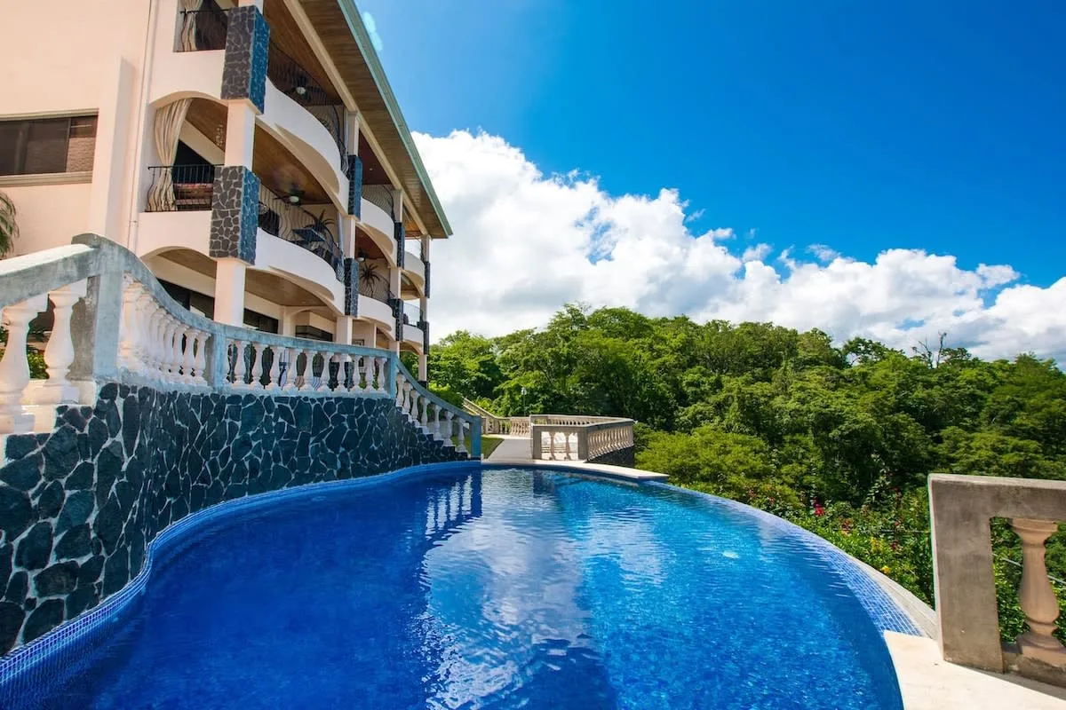 Shared amenity: A curved outdoor pool sits beside a multi-story building and green trees.