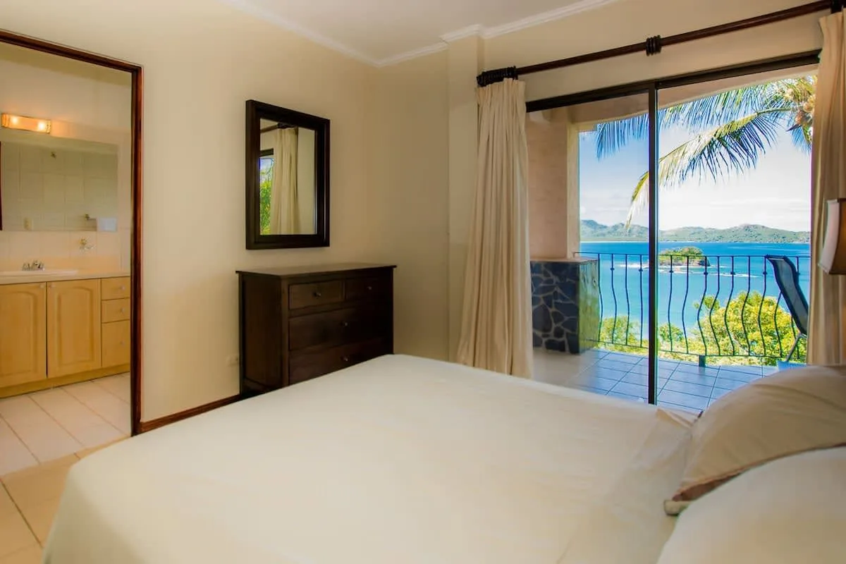 A bedroom with a bed and sliding glass doors opening onto a balcony.