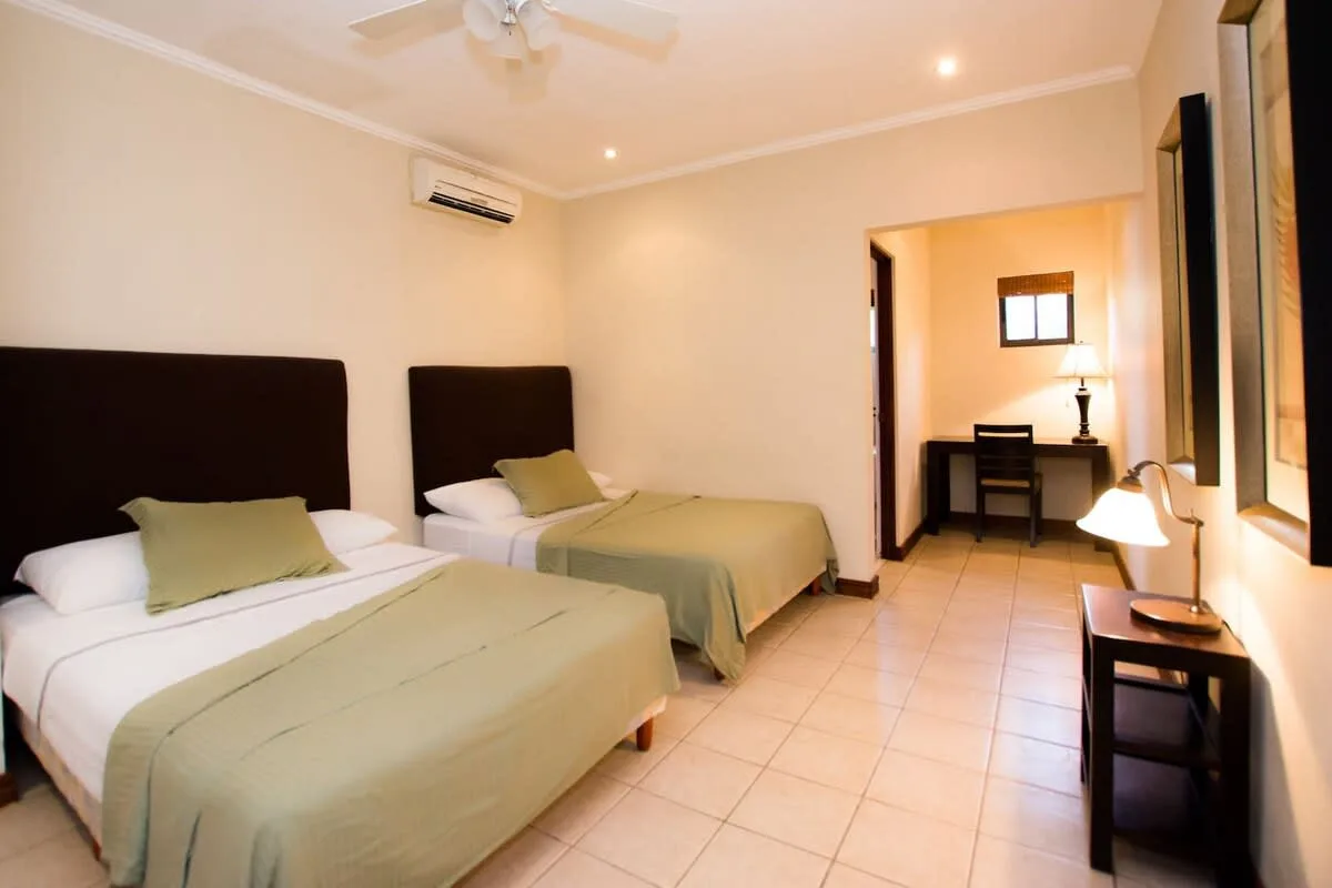 A bedroom with two beds and a desk in the adjoining area.