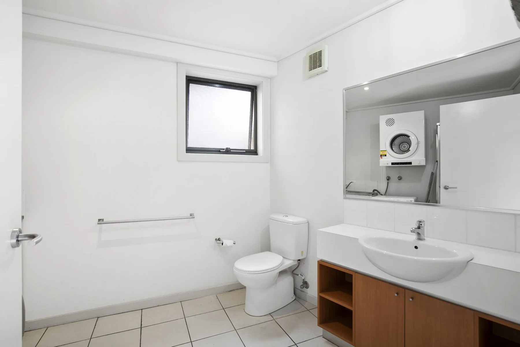 Un baño luminoso con inodoro, suelo de baldosas y lavabo con mueble.