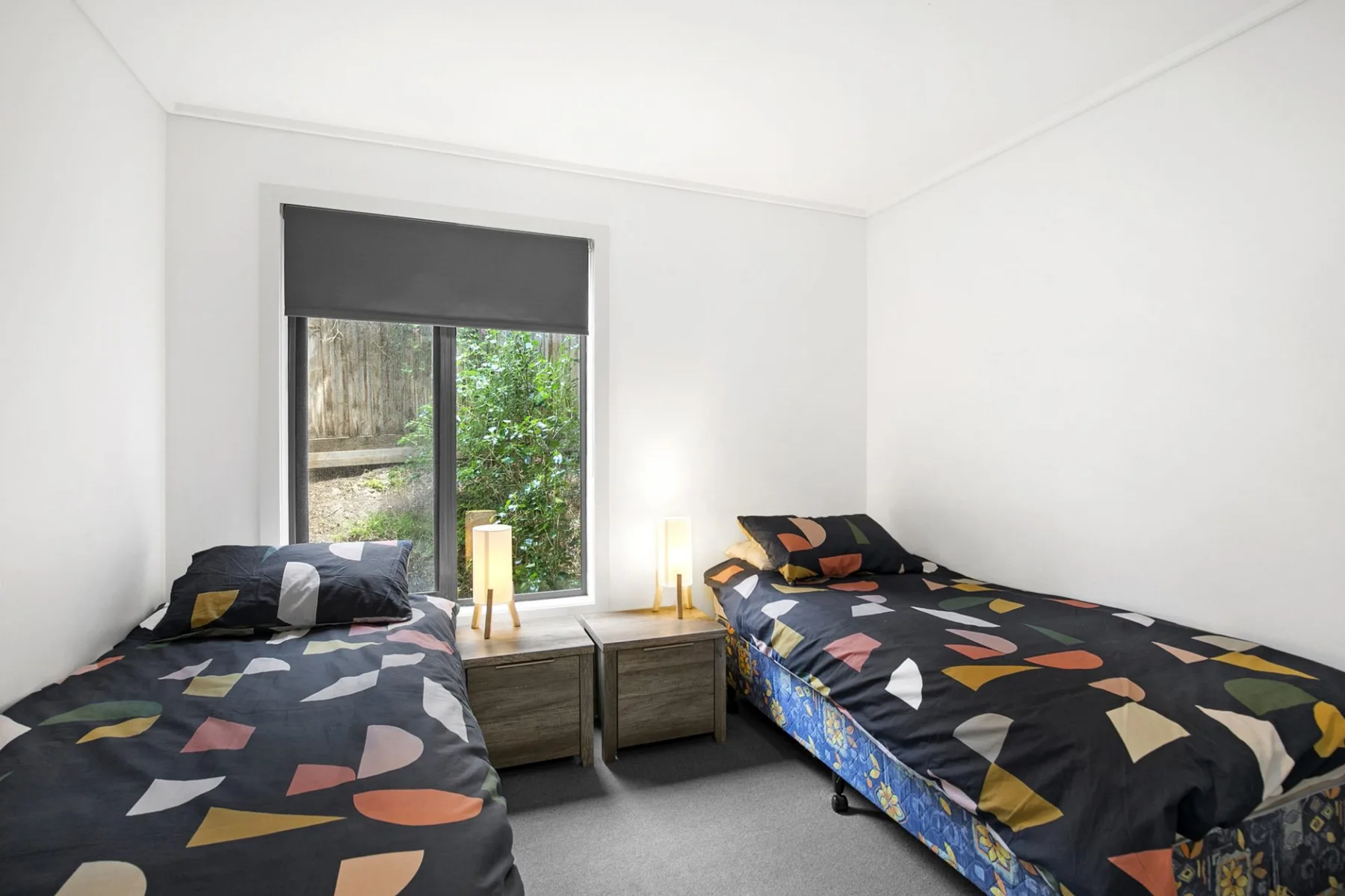 Un dormitorio luminoso con dos camas individuales y una mesita entre ellas.