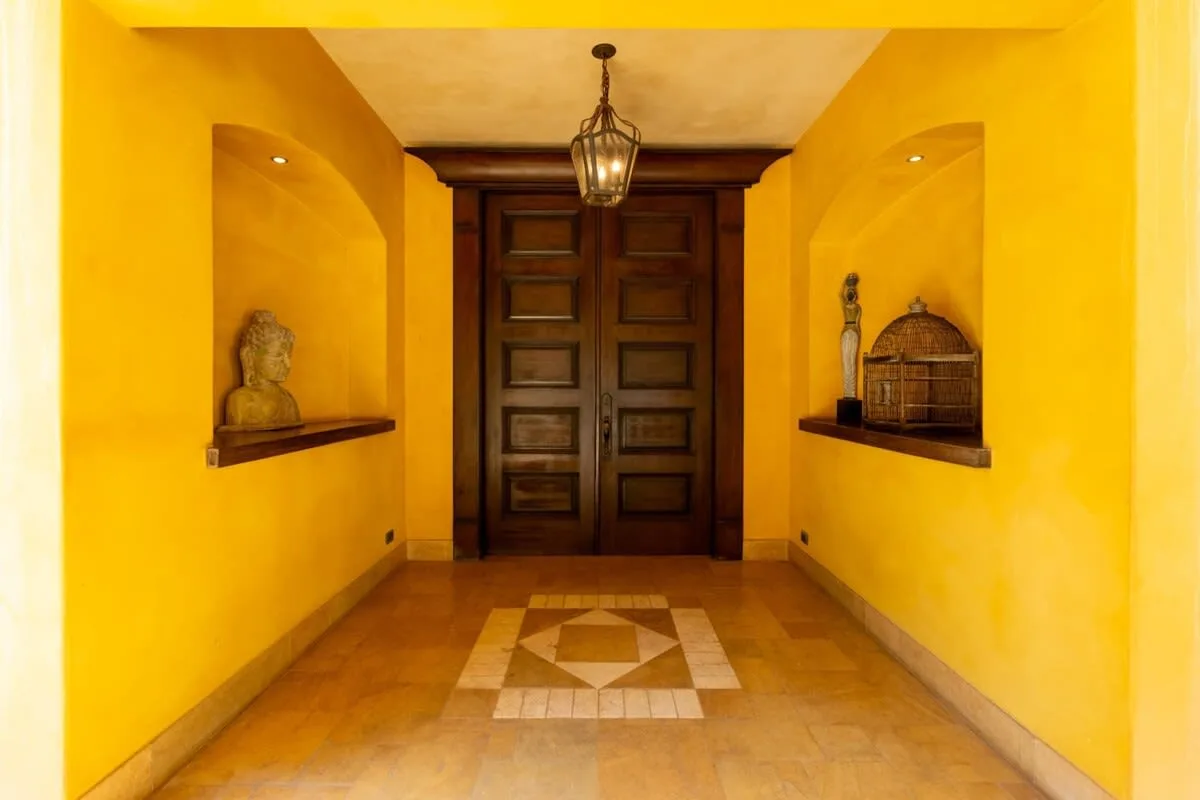A yellow entry hallway features dark wooden double doors and a patterned tile floor.
